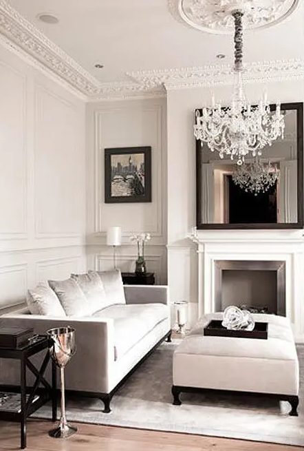 a refined and glam Parisian-style living room done in neutrals, with dark touches for a bit of drama and with gorgeous ornated crown molding and a ceiling medallion