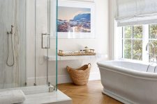 a refined bathroom done with a light-stained parquet floor and white stone slabs, a chic tub and some windows is very welcoming