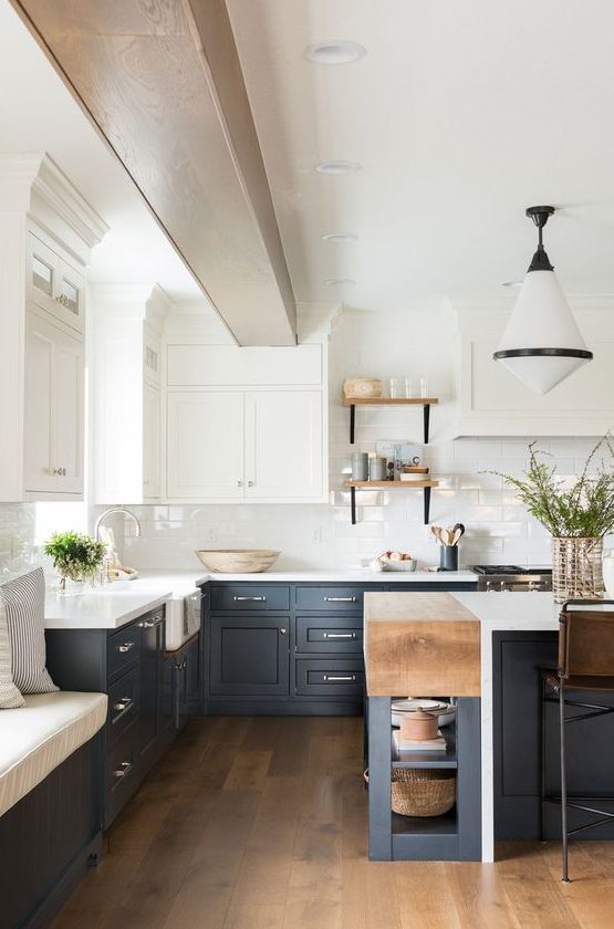a refined two tone kitchen with navy and white shaker style cabinets, white countertops and a subway tile backsplash plus a retro pendant lamp