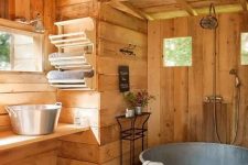 a rustic bathroom of wood, with a galvanized steel bathtub, a vanity with matching steel sinks, some windows