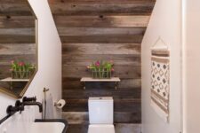 a rustic under the stairs powder room with reclaimed wood, a rustic wall-mounted sink, a small shelf and a geometric mirror