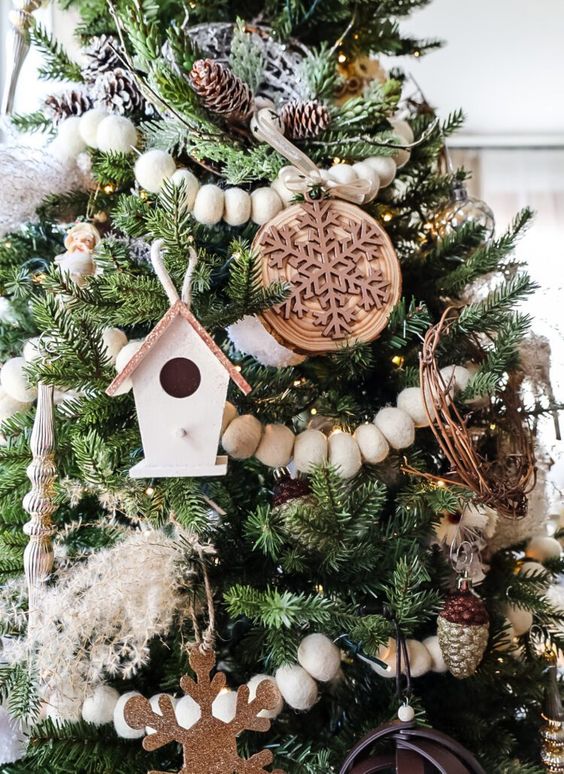 a rustic woodland Christmas tree with ornaments, pinecones, wooden beads, tree slice snowflake ornaments and other stuff