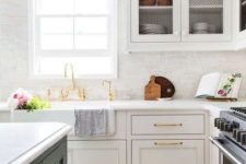 a serene neutral kitchen with sgaker style cabinets, crown molding that connects the upper cabinetry with the ceiling and gold touches for a more glam feel