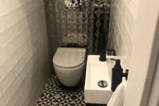 a small modern powder room with white subway and printed black and white tiles, a wall-mounted vanity and a mirror