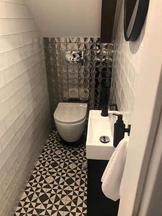 a small modern powder room with white subway and printed black and white tiles, a wall-mounted vanity and a mirror