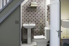 a small modern under stair powder room clad with geo print tiles, with simple white appliances and a mirror is amazing