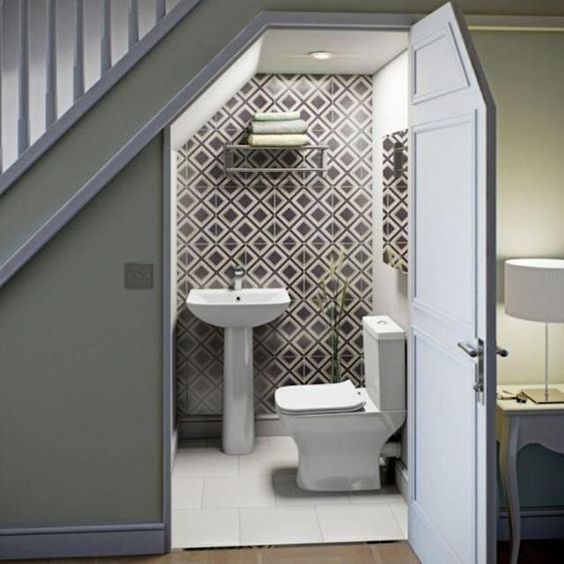 a small modern under stair powder room clad with geo print tiles, with simple white appliances and a mirror is amazing