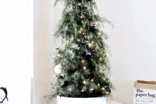 a small potted black and white cedar Christmas tree with ornaments and lights is a cool solution for a minimalist or super modern space
