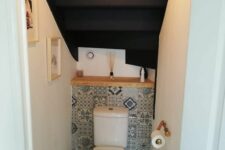 a small powder room under the stairs with a bold tile, a wooden shelf, some decor and a pendant lamp is a cool soluton for a tiny space