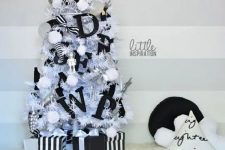 a small white Christmas tree decorated with white pompoms, black letters, black and white ribbons, robots and a star topper is great for a kid’s space