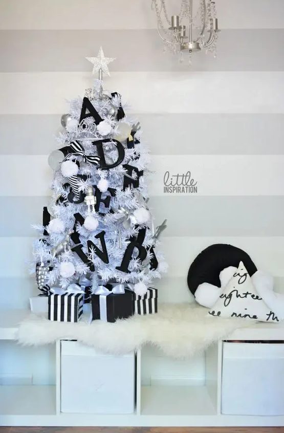 a small white Christmas tree decorated with white pompoms, black letters, black and white ribbons, robots and a star topper is great for a kid's space
