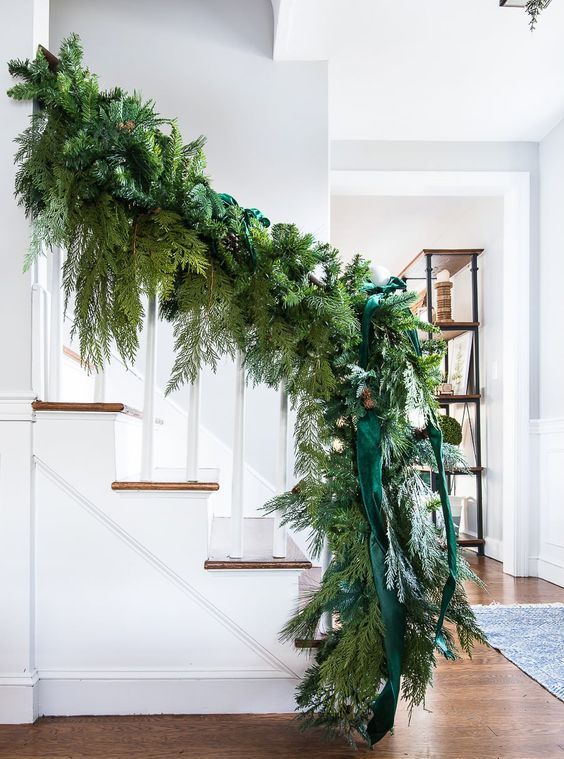 a super lush evergreen garland with emerald ribbons and pinecones is a beautiful solution to style your home for the holidays