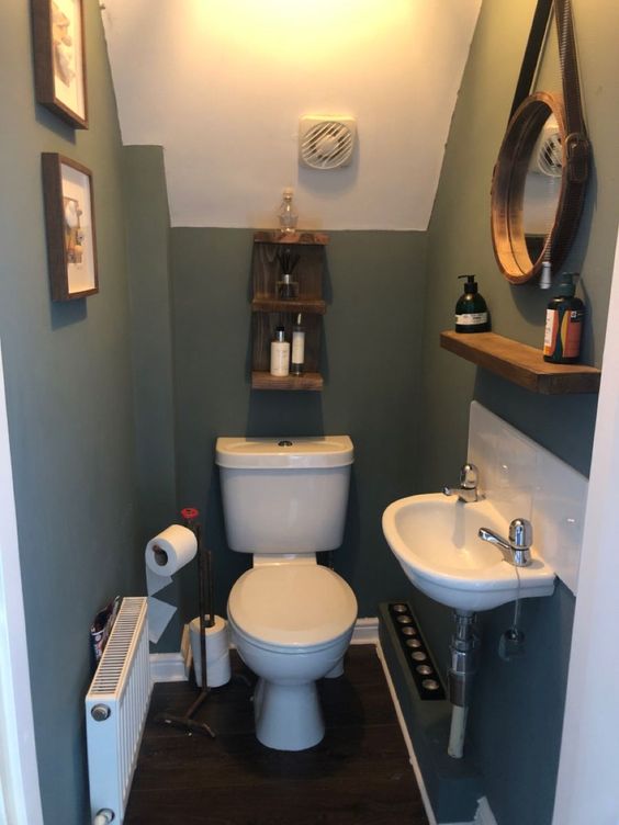 a teal powder room with white appliances, an open shelf, a mirror hanging, some decor and a radiator