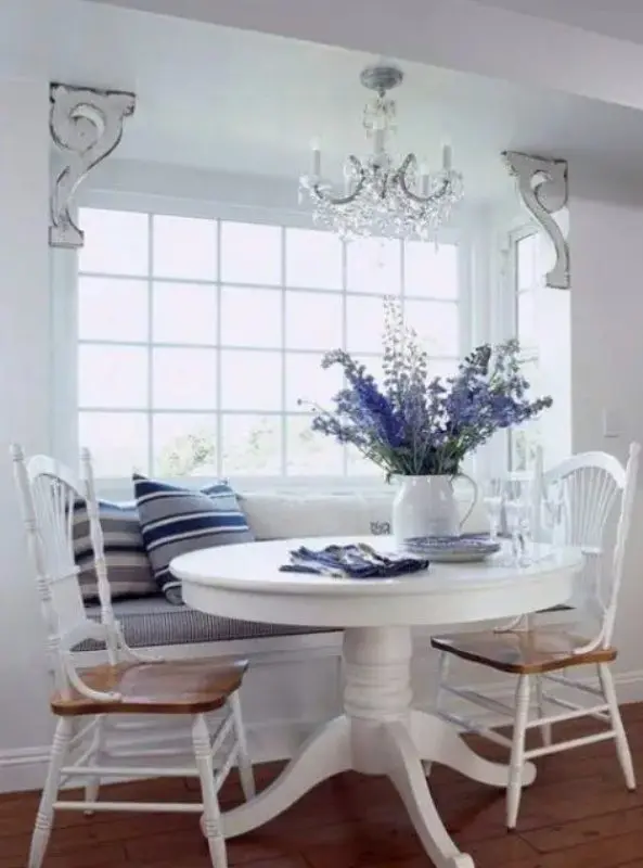 a vintage nautical dining space with a built-in banquette seating and a round table plus vintage chairs and striped pillows