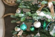 a vintage rustic Christmas tree decorated with light and emerald green ornaments, burlap bows and chain garlands is chic