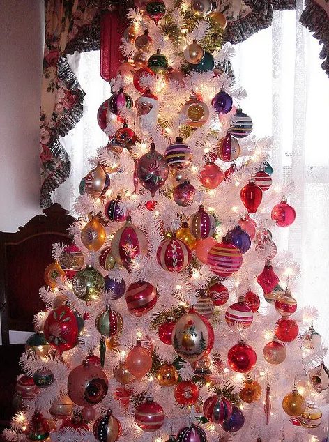 a vintage white Christmas tree with lots of colorful ornaments and lights is a cool idea with plenty of color