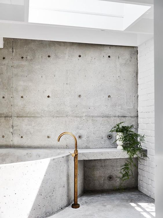 a wabi sabi bathroom with a skeylight and all concrete everything here, a potted plant and elegant fixtures is cool