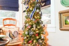 a whimsy woodland glam Christmas tree with lots of snowy pinecones, lights, a large striped bow on top is an amazing idea to try
