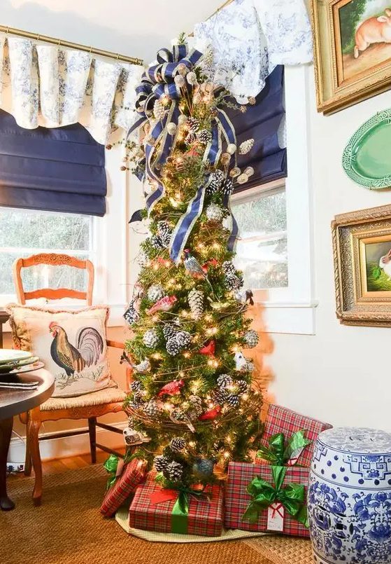 a whimsy woodland glam Christmas tree with lots of snowy pinecones, lights, a large striped bow on top is an amazing idea to try