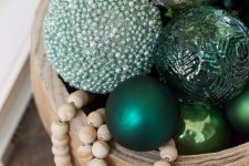 a wooden bowl with green and embellished ornaments, wooden beads is a cool Christmas decor idea