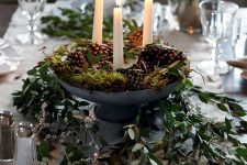 a woodland Christmas centerpiece of a metal bowl with pinecones, candles, moss and greenery is a lovely idea