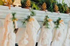a woodland Christmas mantel with pinecones, evergreens, tabletop Christmas trees, knit stockings, mushrooms and evergreens