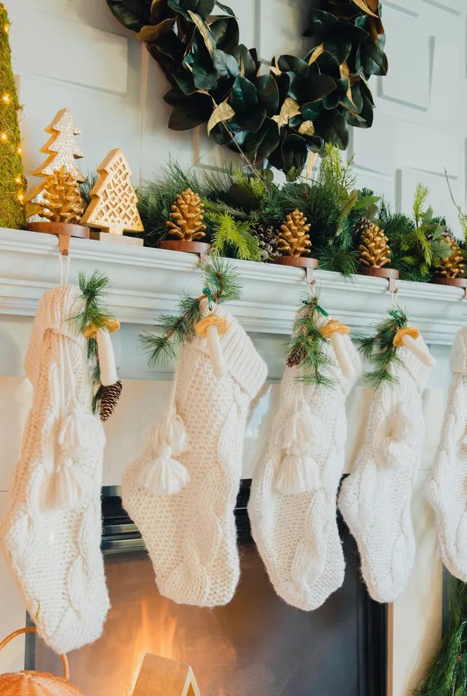 a woodland Christmas mantel with pinecones, evergreens, tabletop Christmas trees, knit stockings, mushrooms and evergreens