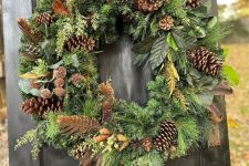 a woodland Christmas wreath with feathers, pinecones and evergreens is a very natural and pretty decoration