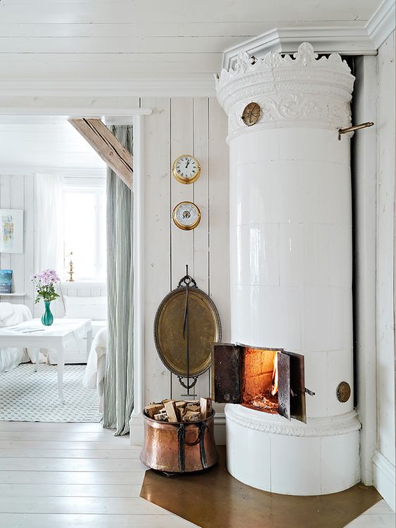 an airy and dreamy Scandinavian space with planked wooden walls and a ceiling, with a white hearth and crown molding is amazing