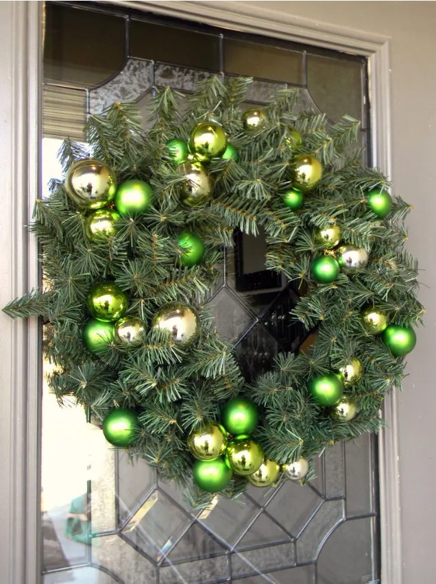 an evergreen Christmas wreath with green and gold ornaments is a stylish idea for the holidays