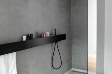 an ultra-minimal bathroom of concrete, a black floating shelf and black fixtures looks chic and elegant