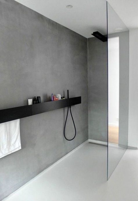 an ultra-minimal bathroom of concrete, a black floating shelf and black fixtures looks chic and elegant
