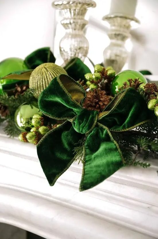 beautiful Christmas decor with light green and green glitter baubles, an emerald velvet bowm pinecones, beads and evergreens