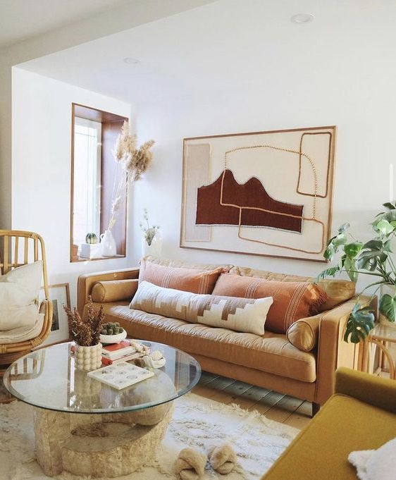 a welcoming boho living room with a yellow sofa and earthy pillows, a mustard loveseat, a rattan chair, a Moroccan blanket rug and a glass table
