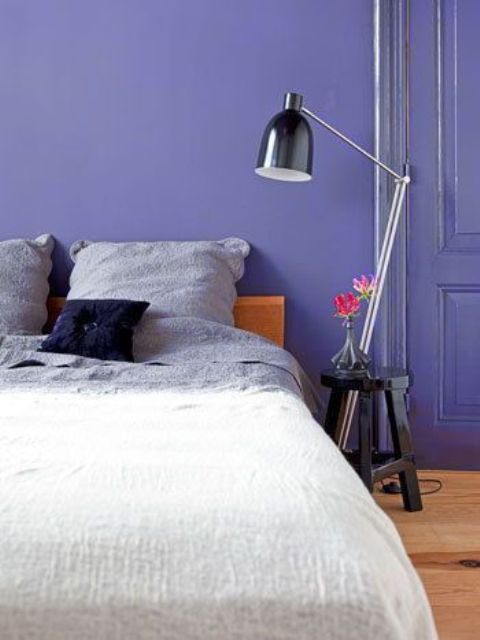 a very peri bedroom with a stained bed and neutral bedding, a black stool and a floor lamp is a catchy idea