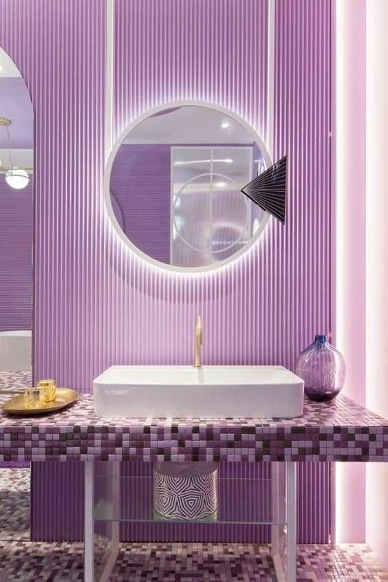 a beautiful very peri bathroom with ribbed walls, a tiled vanity and a white sink plus a lit up mirror