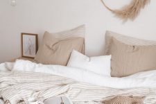 12 a beautiful and relaxed warm neutral bedroom with tan and white bedding, with a pampas grass wreath and some art