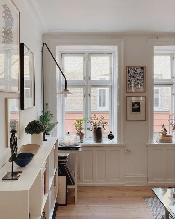 a welcoming Scandinavian space with creamy paneling and furniture, artwork, black touches for more drama in the room