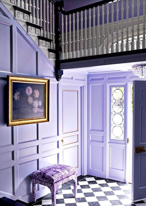 a sophisticated entryway with very peri walls, a purple ottoman and a floral artwork is a very chic space