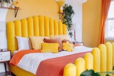 24 a bright bedroom with a sunny yellow wall and an accent, a yellow upholstered bed, red touches and potted greenery