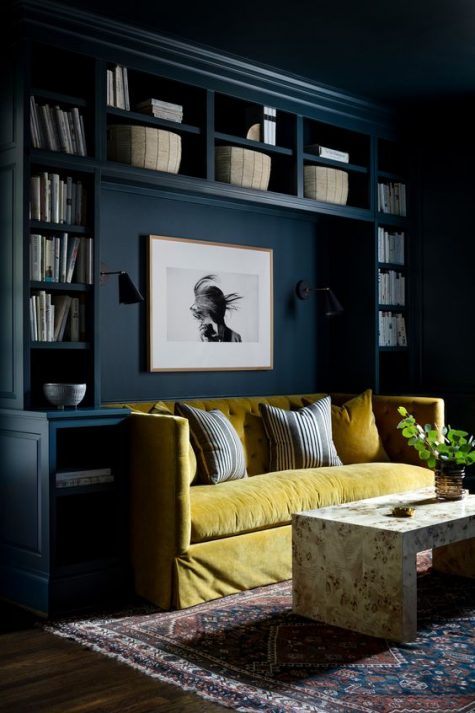 a moody navy room with a bold yellow velvet sofa for a statement and a marble table that adds chic to the space