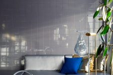 28 a neutral space with a tiled wall, a grey sofa, a very peri rug for a super bold accent, gold pillows and a bold blue one