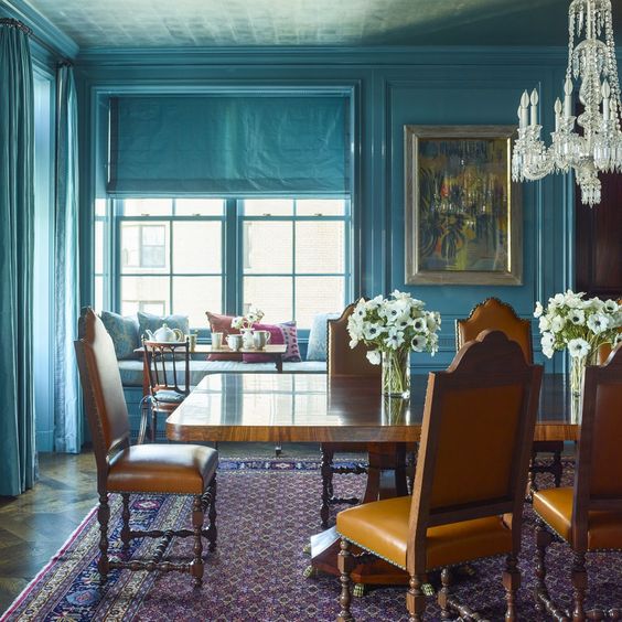 a stone blue dining room with vintage dinign furniture, a crystal chandelier and some vintage art is very chic