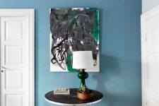 31 a beautiful stone blue space, a bold artwork, a black and navy side table and a bold lamp with a green base