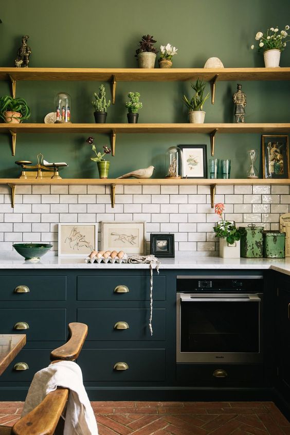 a lovely green kitchen with teal cabinetry, a white subway tile backsplash, white countertops and potted plants
