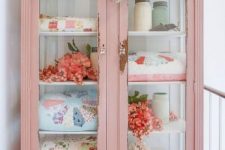 37 a shabby chic pink cabinet with glass doors repurposed for storing blankets and other stuff is amazing for a cottage-inspired interior