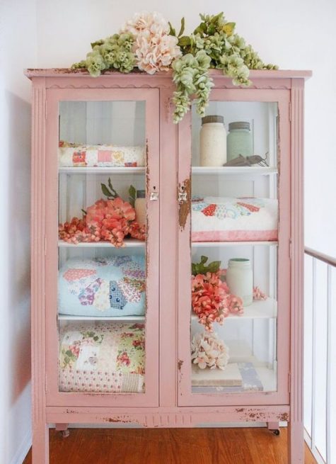 a shabby chic pink cabinet with glass doors repurposed for storing blankets and other stuff is amazing for a cottage-inspired interior