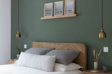 38 a delicate bedroom with a sage green accent wall, a wooden bed and nightstands, brass pendant lamps and artwork