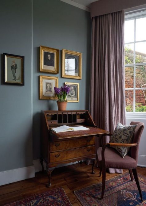 a sophisticated vintage dark-stained desk with elegant legs and a mauve chair that matches for a chic working space