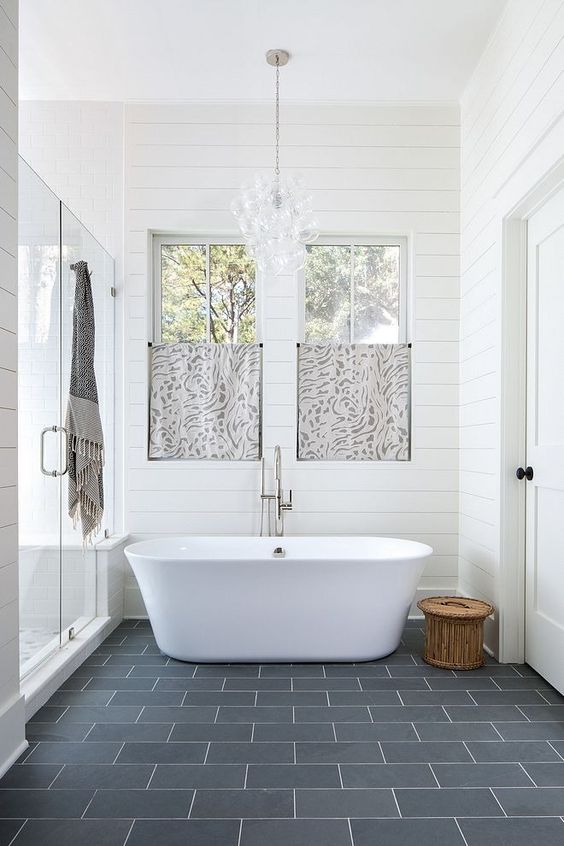 a beautiful master bathroom with shiplap walls, ample natural light, and a free-standing soaking tub